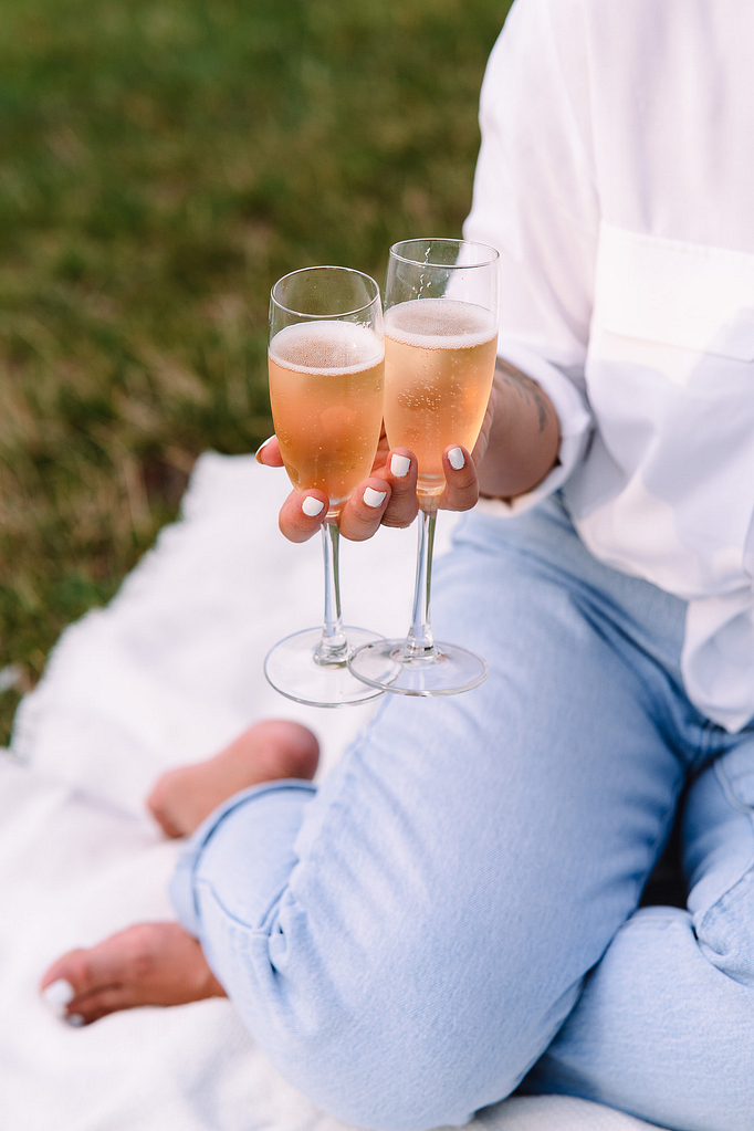 Photo d'une femme tenant deux coupes de champagne lors d'un pique nique dans un parc
